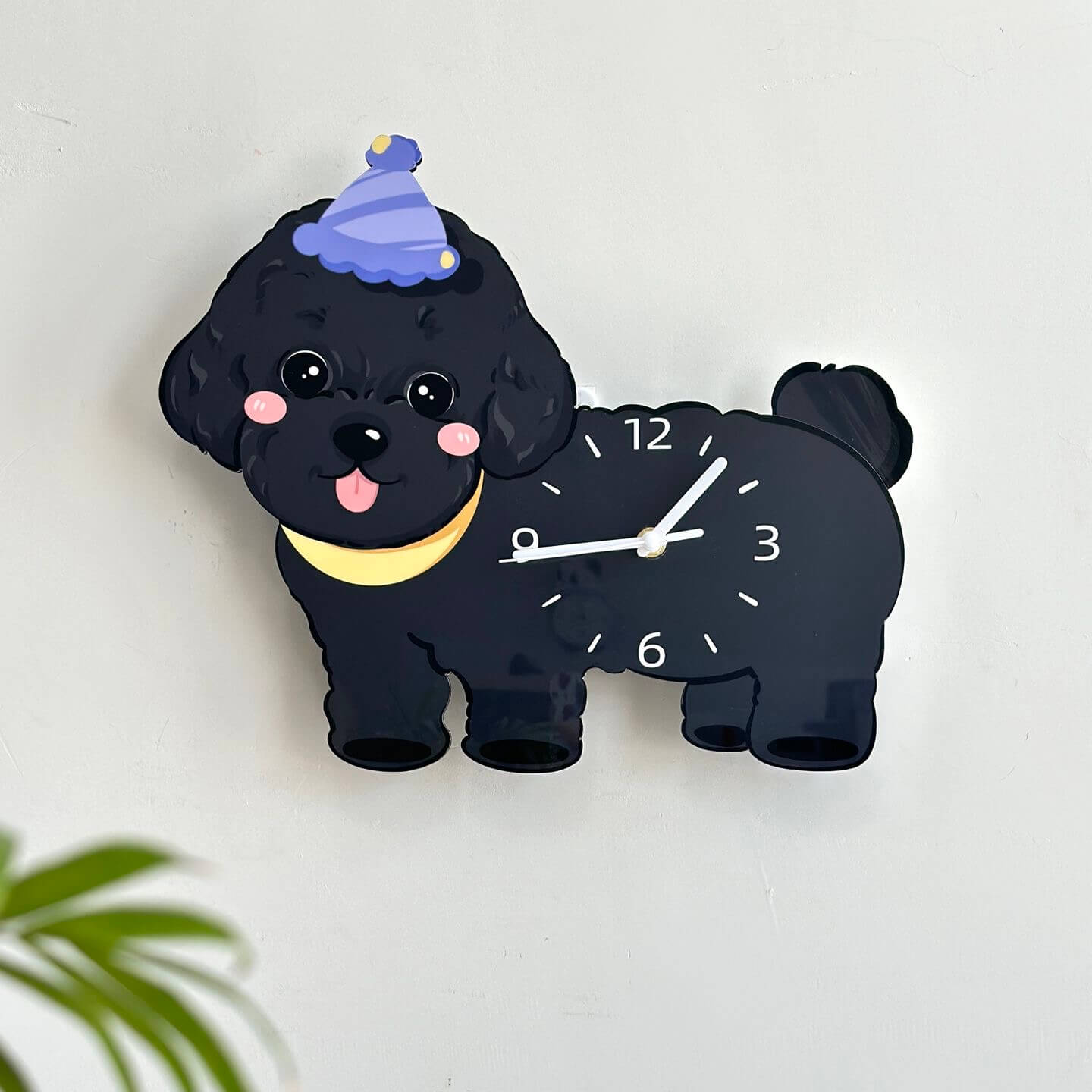 Black poodle wall clock on cream wall with blurred plant leaves in foreground