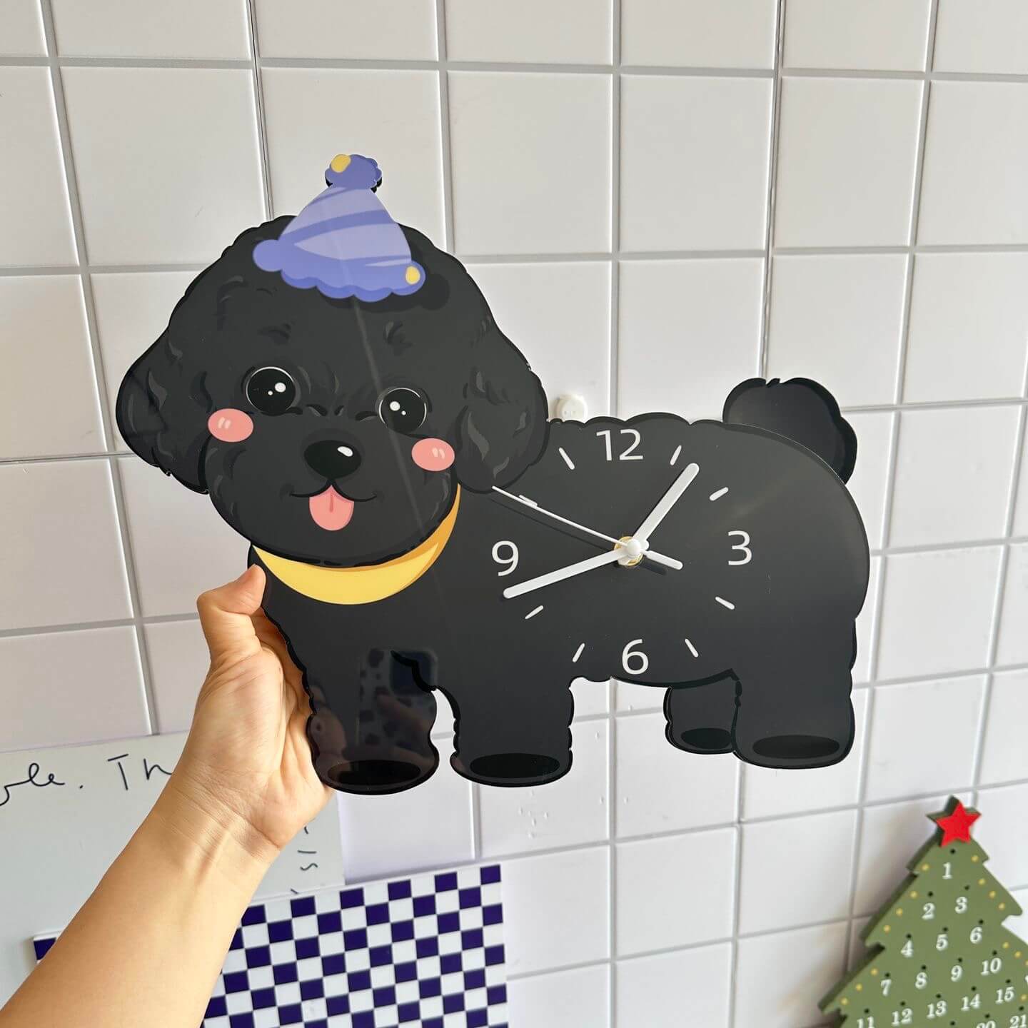 Black poodle wall clock on white tile wall with advent calendar and Christmas tree