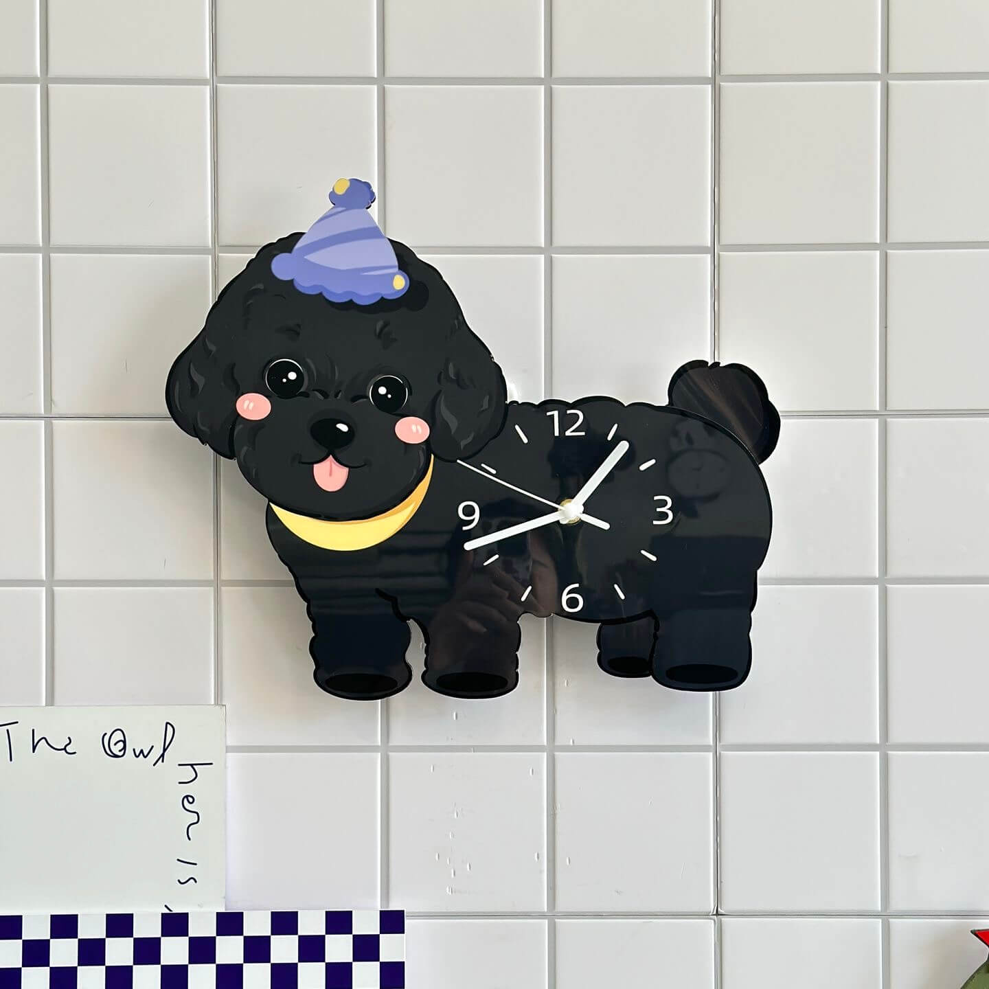 Black poodle dog clock on white tile wall with The Owl decorative sign and checkered cloth
