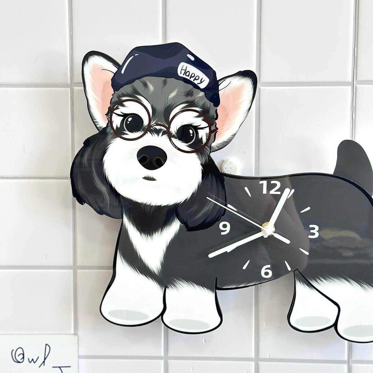 Close-up of Schnauzer dog clock wearing glasses and a navy Happy cap on a white tiled wall