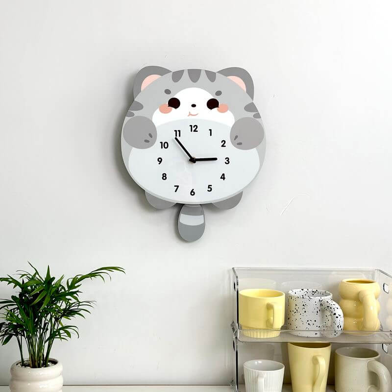 British Shorthair blue cat wall clock mounted on clean white wall with green plant decor