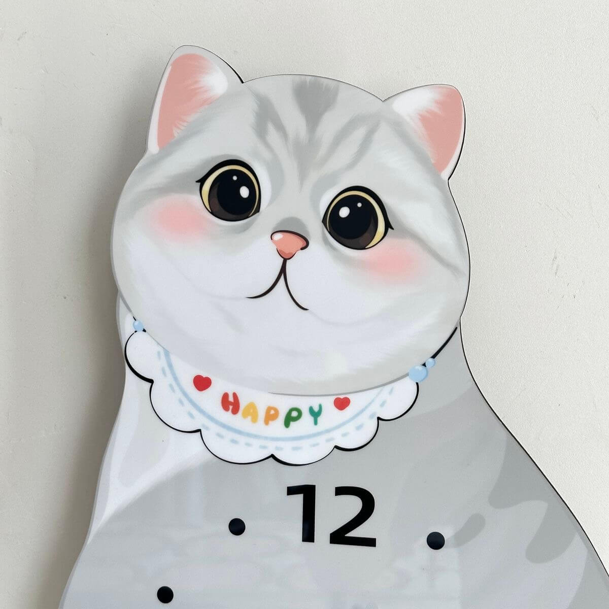 British Shorthair silver shaded clock front view on white wall with green plant
