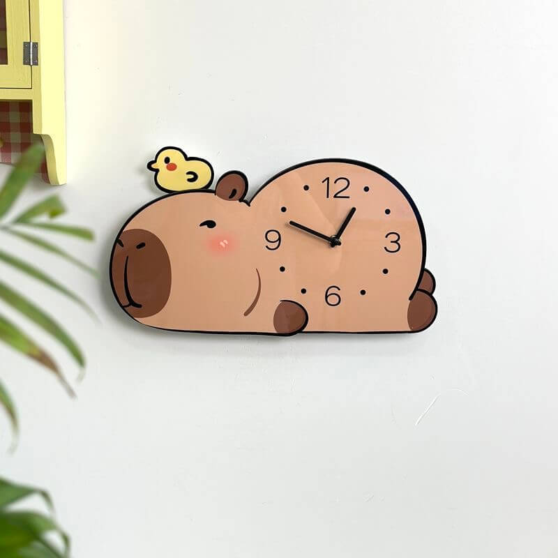 Capybara sleepy clock on cream wall with yellow cabinet and blurred plant in foreground