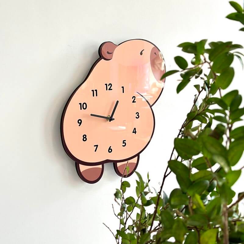 Capybara lying wall clock mounted on clean white wall with green plant decor