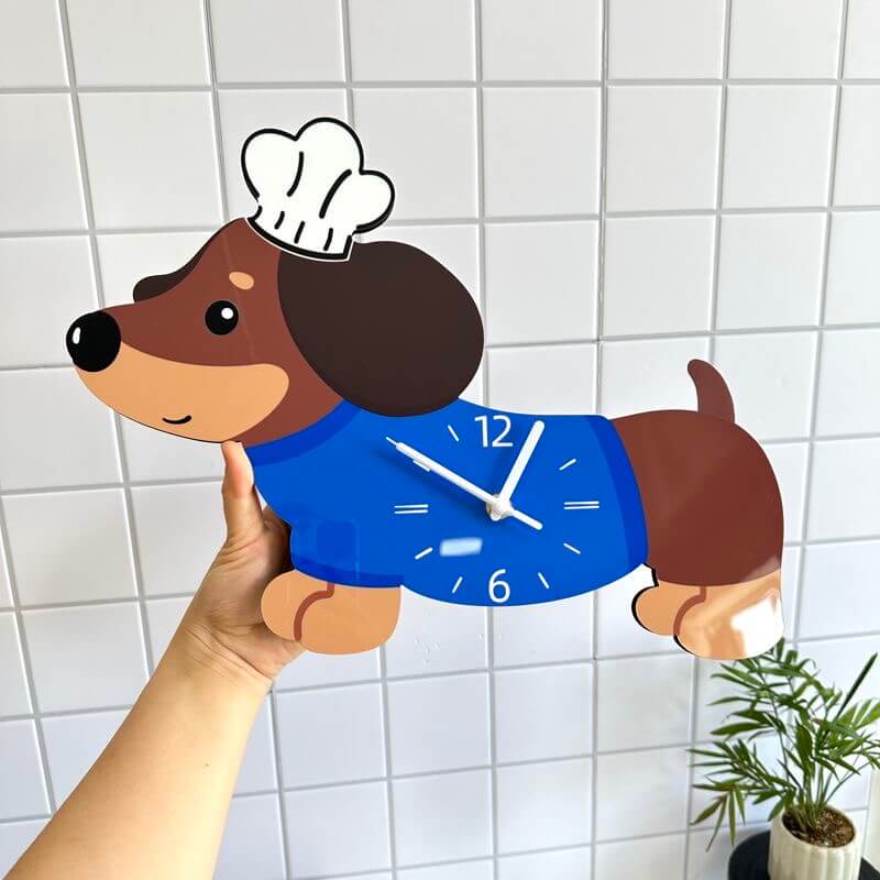 Dachshund dog clock held by hand in front of white tile wall with potted plant