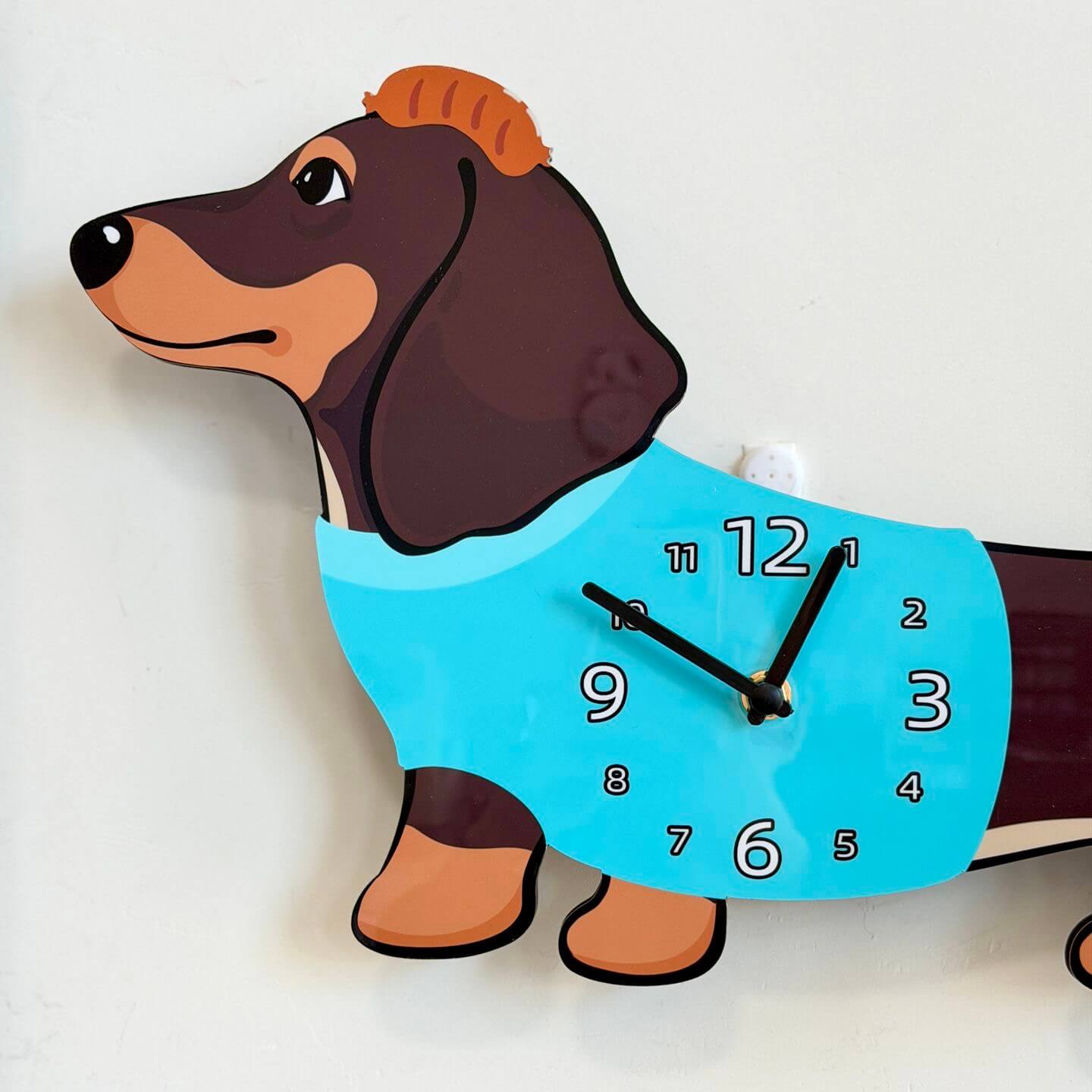 Dachshund dark brown wall clock mounted on clean white wall with green plant decor