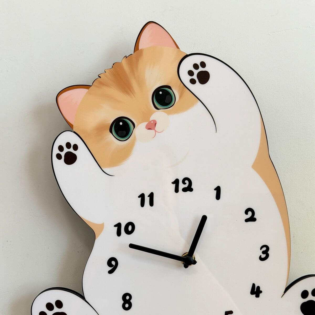 Orange tabby cat wall clock angled view showing cute paw pads and green eyes