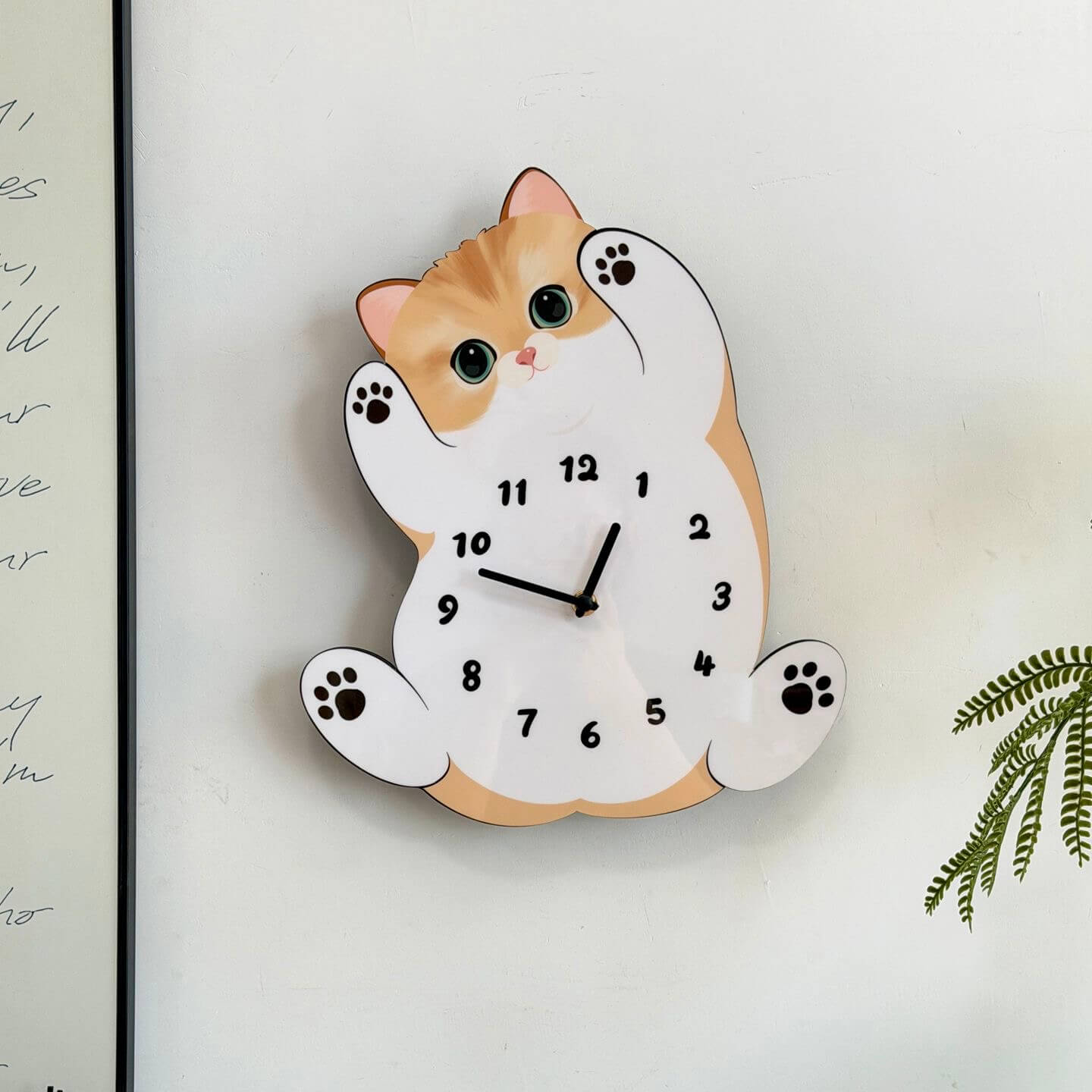 Orange tabby cat wall clock mounted on clean white wall with green fern plant decor