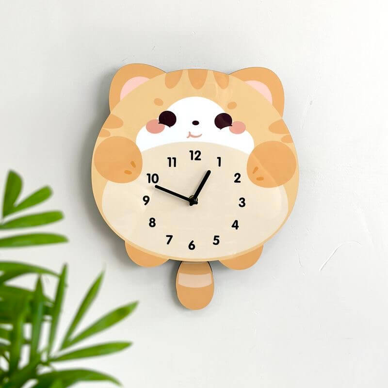 Orange tabby lying cat wall clock mounted on clean white wall with green plant decor