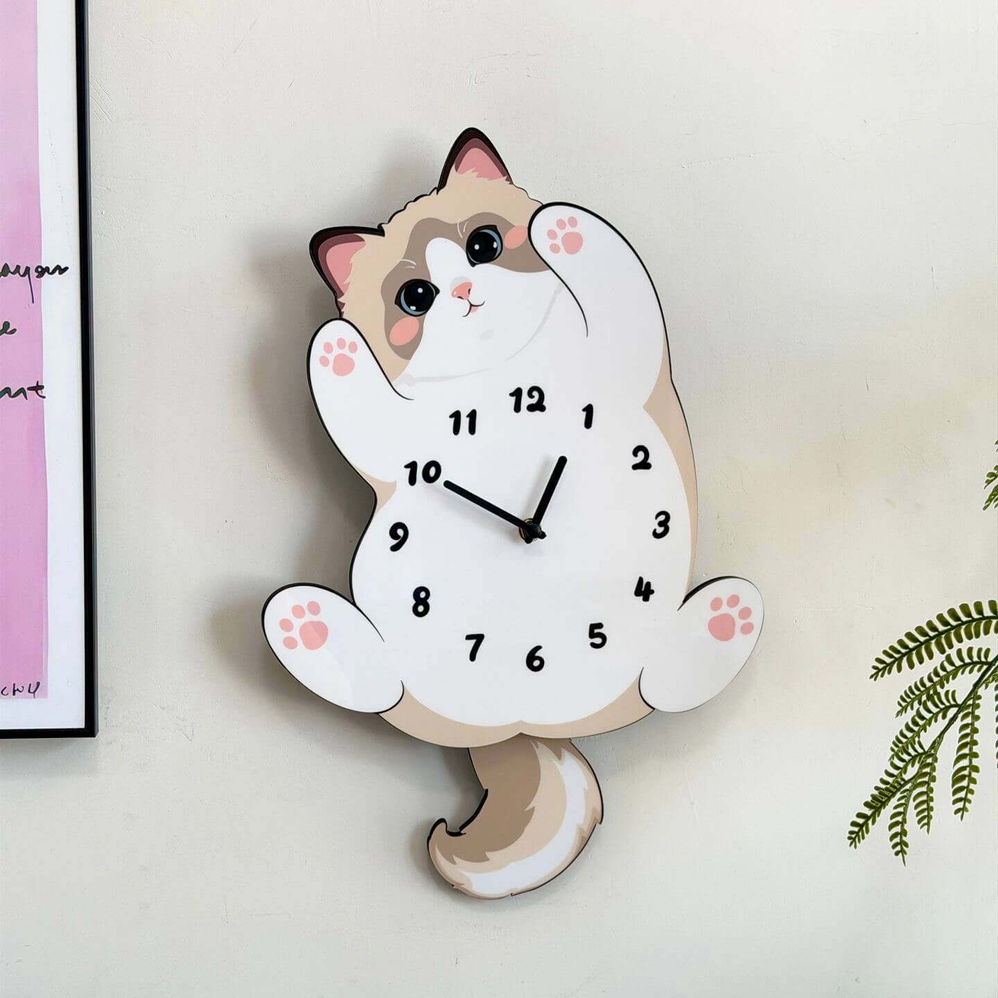 Ragdoll cat wall clock on cream wall with green plant leaves and reed diffuser